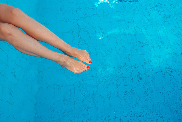 ενηλίκων λευκό καυκάσιο Ευρωπαϊκό πόδι γυναίκα με πορτοκαλί υπεριώδες πεντικιούρ υποβρύχια στην πισίνα. Καλοκαίρι. Διακοπές και Αθλητισμός έννοια. - Φωτογραφία, εικόνα