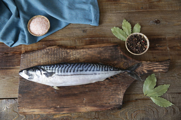 Fresh mackerel with spices on a wooden cutting board and wooden rustic background with copy space for text, flat lay. Top view. - Photo, Image