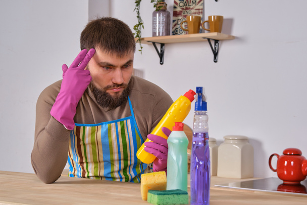 Молодой человек хотел помочь своей жене в уборке, но он не знает, что делать со всеми моющими средствами
 - Фото, изображение