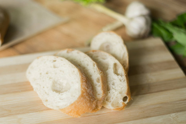 Sliced bread, ciabatta on wooden background. Preparation for the preparation of bruschetta. - Foto, imagen