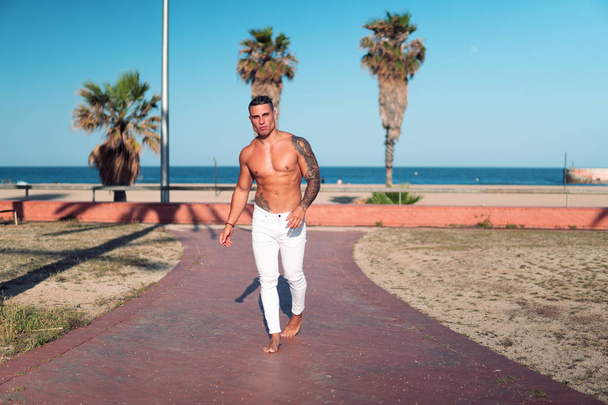 Tattooed bodybuilder sexy male coach at the beach. - Фото, изображение
