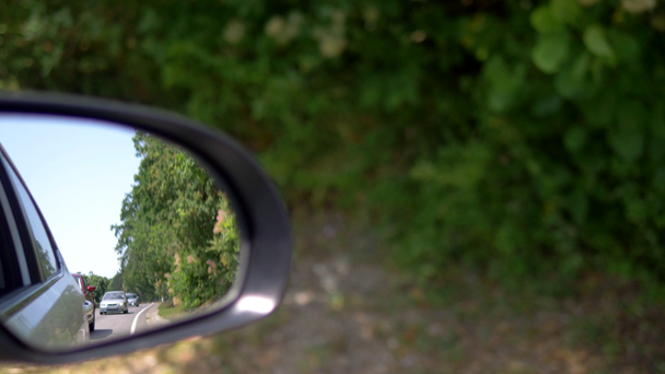 Reise- oder Verkehrskonzept. Rückspiegel, der die Autoschlange auf der Straße im Grünen während der Fahrt widerspiegelt - Filmmaterial, Video