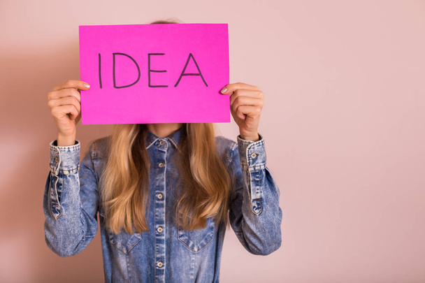 Nainen, joka pitelee paperia sanalla "idea" seistessään seinän edessä
. - Valokuva, kuva