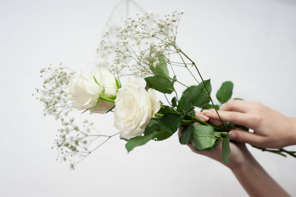a női kezek fehér alapon finom fehér rózsákat tartanak - Fotó, kép