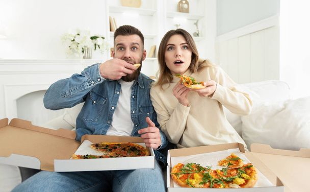 ホラー映画を見て、ピザを食べるミレニアルカップル - 写真・画像