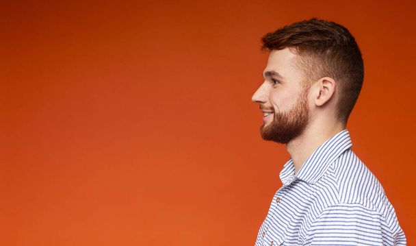 Side view portrait of smiling millennial man on red - Fotografie, Obrázek