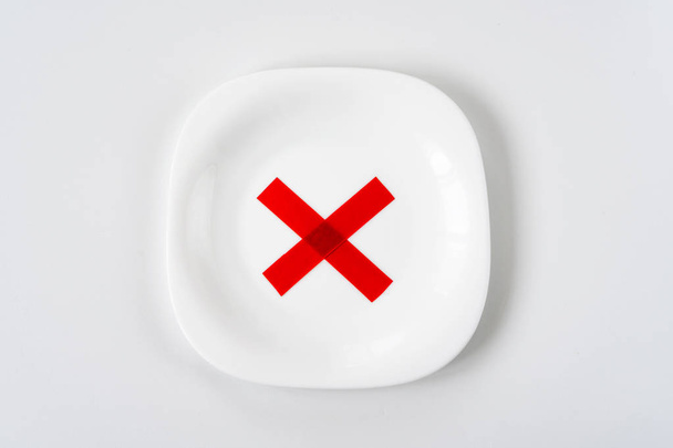 white plate with with red X cross mark on it on white table. Die - Photo, Image