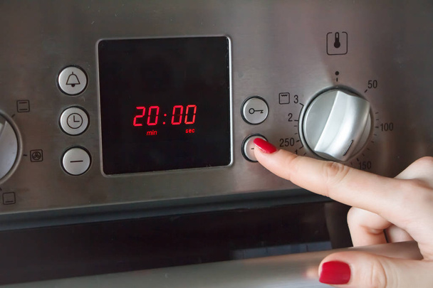 Uma mão de mulher põe no forno um tempo de 20 minutos e uma temperatura de 180 graus para fazer torta de maçã
 - Foto, Imagem