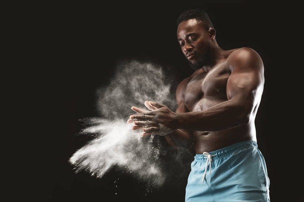 Joven deportista afroamericano de pecho desnudo aplicando talco en polvo
 - Foto, Imagen