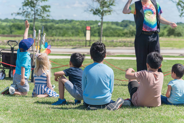 Vue arrière enfants multiculturels sur herbe prairie levant les mains dans le jeu de plein air
 - Photo, image