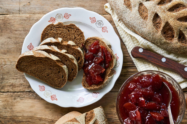Slices of rye bread with plum jam on a wooden table                                - Φωτογραφία, εικόνα