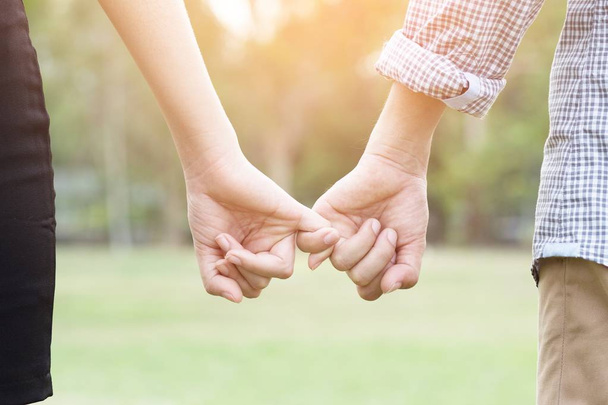 Couple lovers holding hands towards the sun with bright sun flare in parks, or close up view in a conceptual image first love and puppy love adolescent young. - Photo, Image