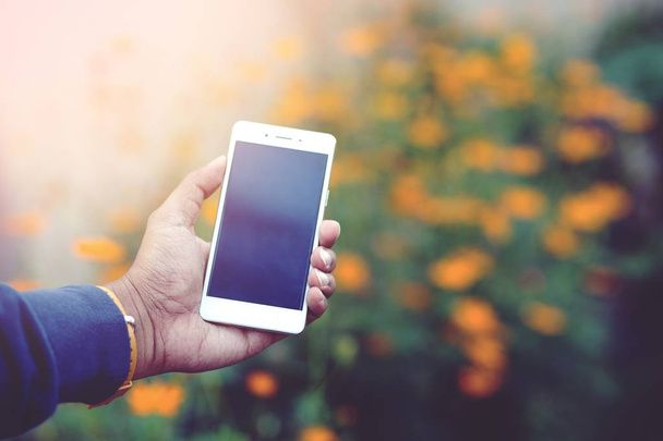 Zobrazit telefon v ruce žluté pozadí květin - Fotografie, Obrázek