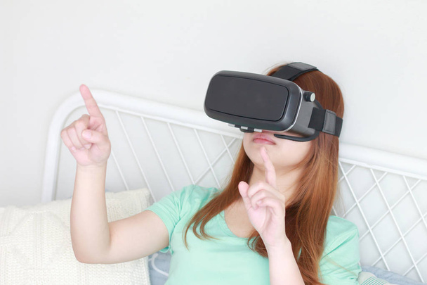 Jonge vrouw met virtual reality bril thuis. - Foto, afbeelding
