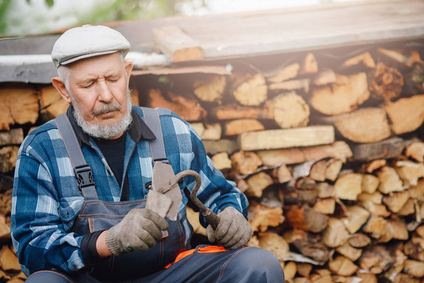 Senior-Mann lächelt und repariert Werkzeug zur Bodenbearbeitung und Unkrautbeseitigung. Landwirtschaftskonzept - Foto, Bild