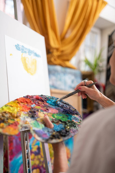 Woman holding color palette mixing colorful gouache and painting - Fotó, kép