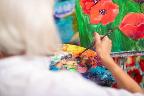 Woman mixing colorful gouache while painting poppies - Photo, Image