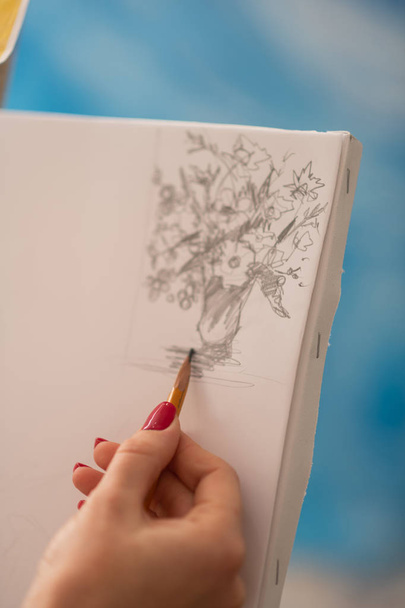Close up of promising artist drawing vase with flowers - Fotó, kép