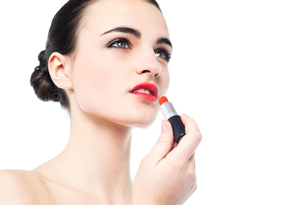 Portrait of beautiful girl applying lipstick - Foto, afbeelding