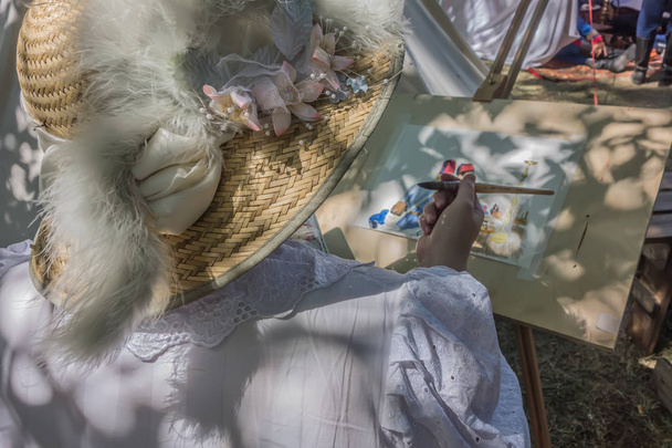 Женщина-художник в красивой соломенной шляпе держит кисть в руке
 - Фото, изображение