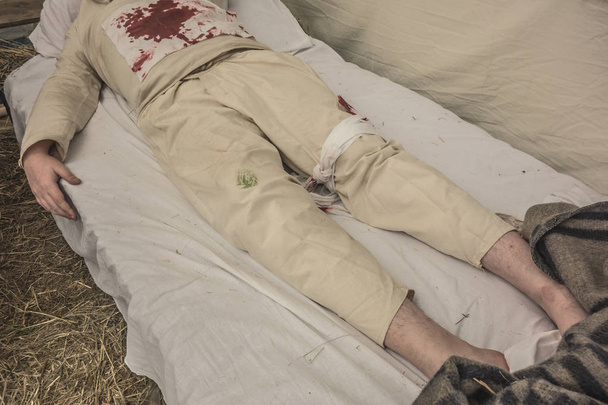 Wounded soldier lying on a hay in a field military hospital. - Photo, Image