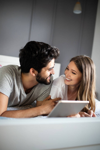 Happy couple in love using tablet in pajamas at home - Foto, afbeelding