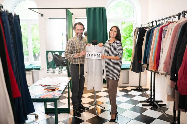 Two happy business partners holding an open sign in hands - Фото, изображение