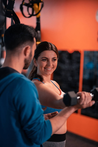 Woman smiling while talking to trainer and doing exercises - Foto, immagini