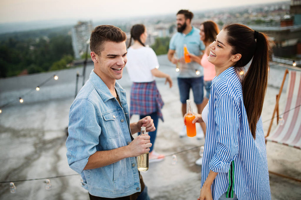 Happy young couple enjoying drinks and balcony party. - Foto, imagen