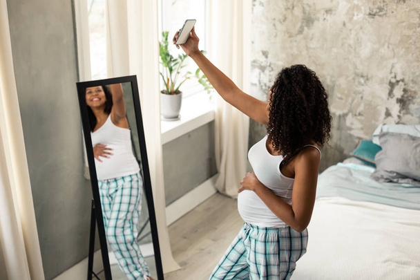 Happy pregnant woman taking a selfie at home. - Zdjęcie, obraz