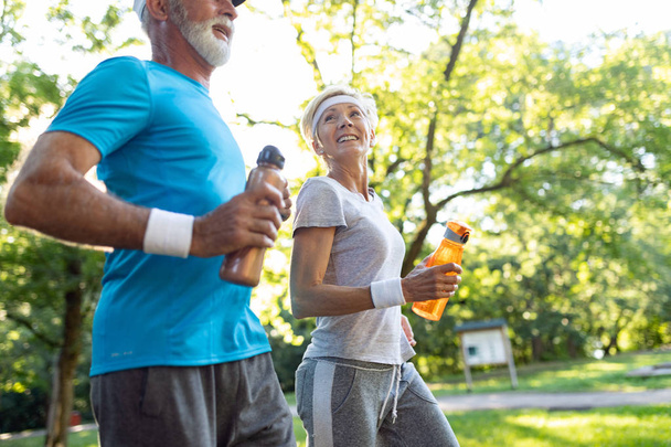 Happy senior couple staying fit by exercise jogging - Foto, Bild