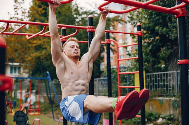 Handsome man training in a summer park - Photo, Image
