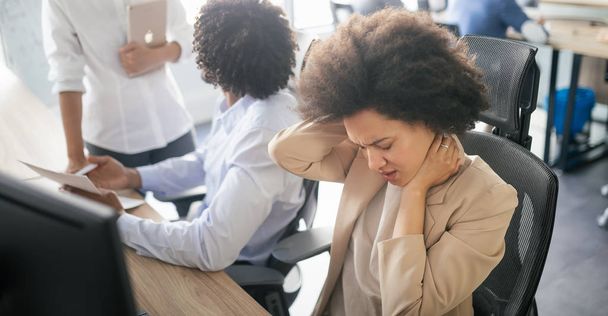 Young black business woman having stress and pain in the office - Foto, afbeelding