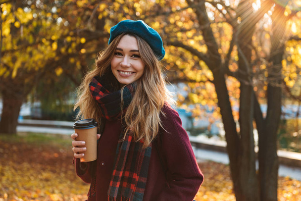 Beautiful young pretty woman walking outdoors in autumn spring park. - 写真・画像