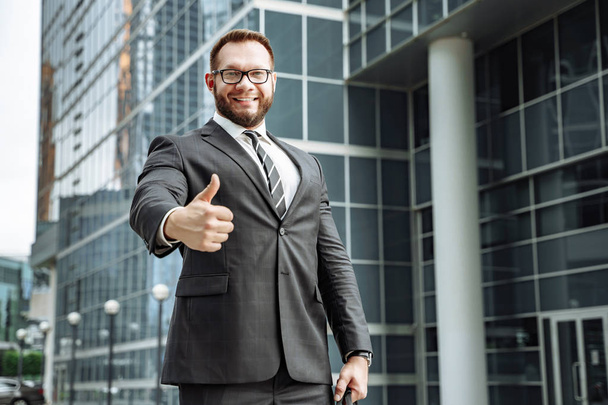 Ritratto di un uomo d'affari felice che mostra il pollice in su sullo sfondo del business center
 - Foto, immagini