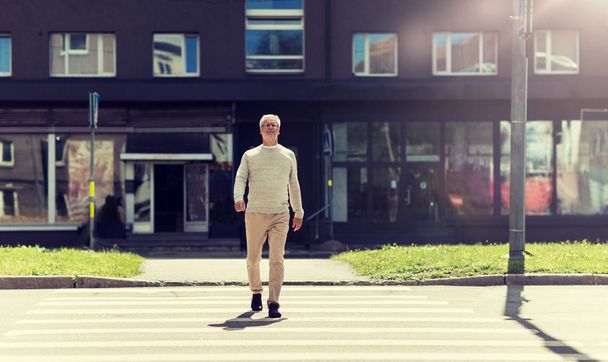 senior man walking along city crosswalk - Fotoğraf, Görsel