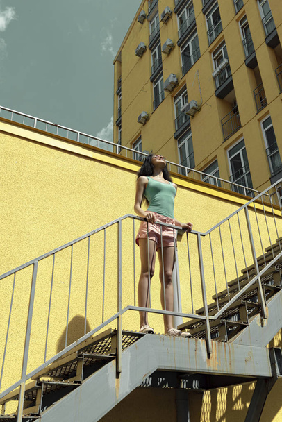 Attractive young woman standing on stairs on the street - Foto, afbeelding