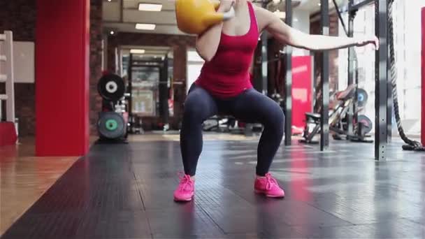 Kettlebell fitness, young female athlete doing strength exercises in the gym - Materiał filmowy, wideo