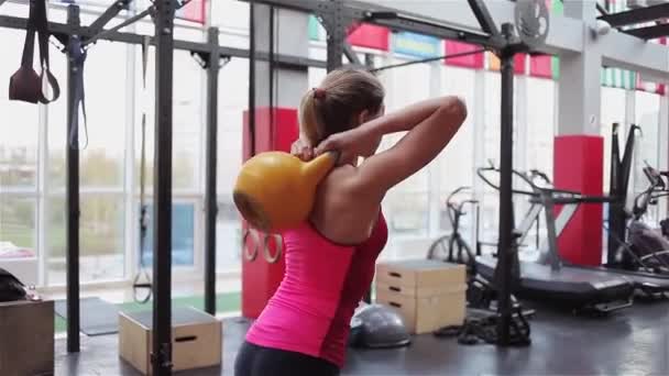 Kettlebell fitness, young female athlete doing strength exercises in the gym - Felvétel, videó