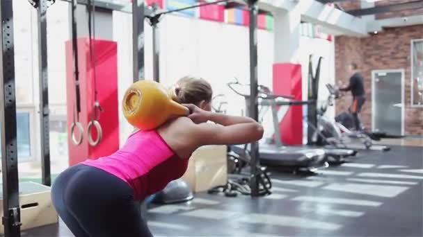 Kettlebell fitness, young female athlete doing strength exercises in the gym - Felvétel, videó