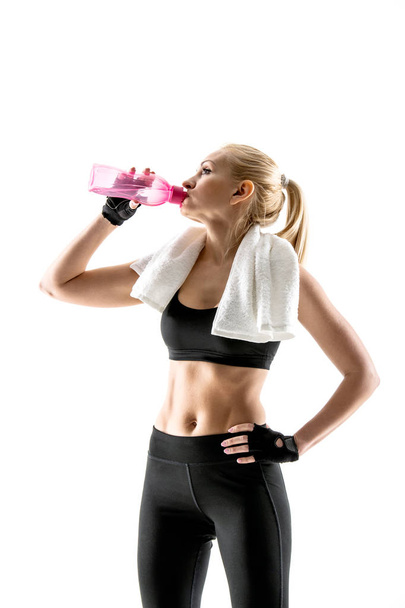 Спортсменка с красивой прессой пьет воду во время тренировки
. - Фото, изображение