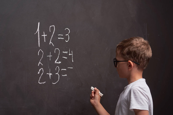 Primary education. Rear view of a schoolboy solves a mathematica - Foto, imagen