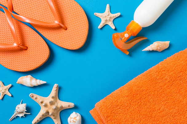 Top view of Beach flat lay accessories. sunscreen bottle with seashells, starfish, towel and flip-flop on Colored background with copy space - Fotografie, Obrázek