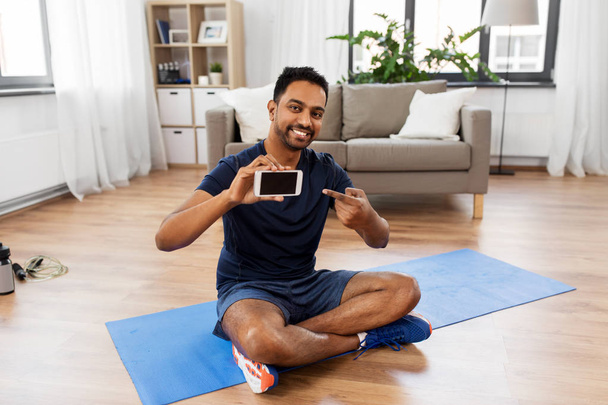 indian man with smartphone on exercise mat at home - Fotografie, Obrázek