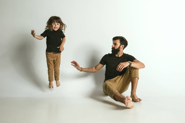 Father playing with young son against white studio background - Foto, afbeelding