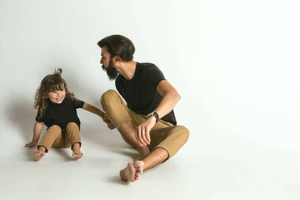 Father playing with young son against white studio background - 写真・画像
