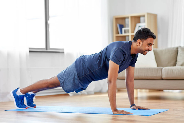 indian man doing push ups at home - Foto, afbeelding