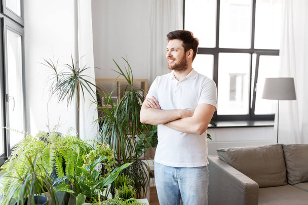 smiling man with houseplants at home - 写真・画像