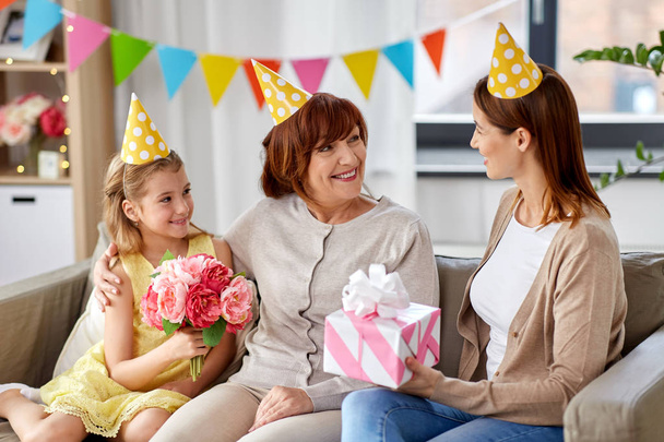 mother with gift greeting grandmother on birthday - 写真・画像