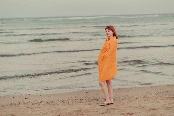 Un salvagente. Una ragazza in un asciugamano caldo si trova vicino al mare
 - Foto, immagini